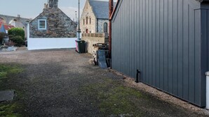 Ein Kiesweg führt zu einem Steinhaus mit rotem Ziegeldach.