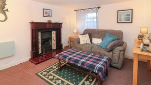 Ein gemütliches Wohnzimmer mit Kamin, Sofa, Tisch und Teppich.