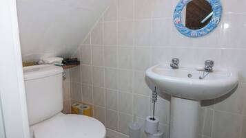 Un baño pequeño con inodoro, lavamanos y espejo.