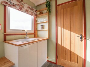Una cocina con ventana, armarios de madera, un lavamanos y una puerta.