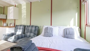 A room with a bed, a sofa, a small table, and a kitchenette area. - Nŷth Y Bioden (Caernarfon)