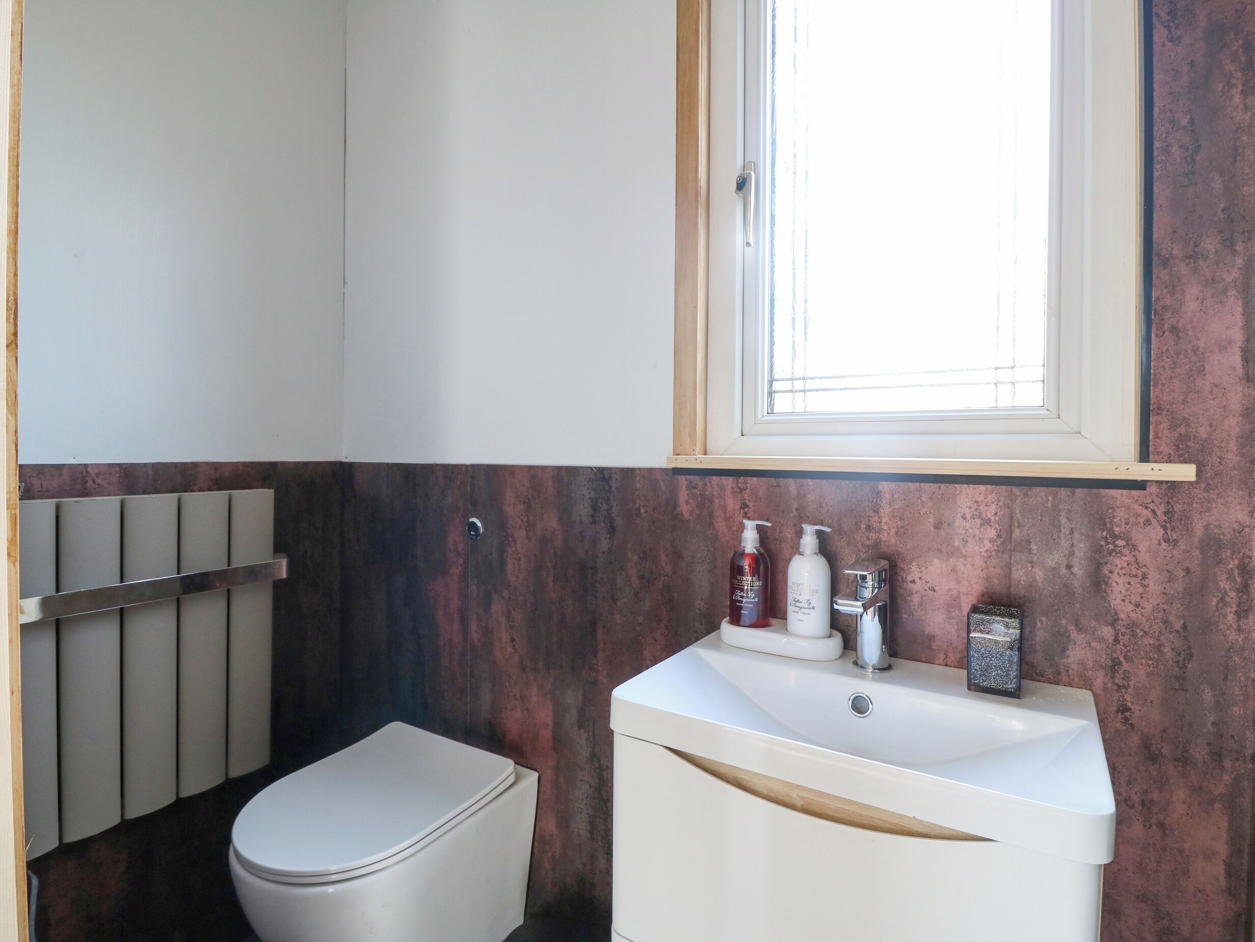 Un bagno con un water, un lavandino con articoli da toilette e una finestra.