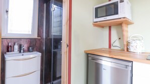 A compact kitchen with a microwave, kettle, and dishwasher. - Nŷth Y Bioden (Caernarfon)