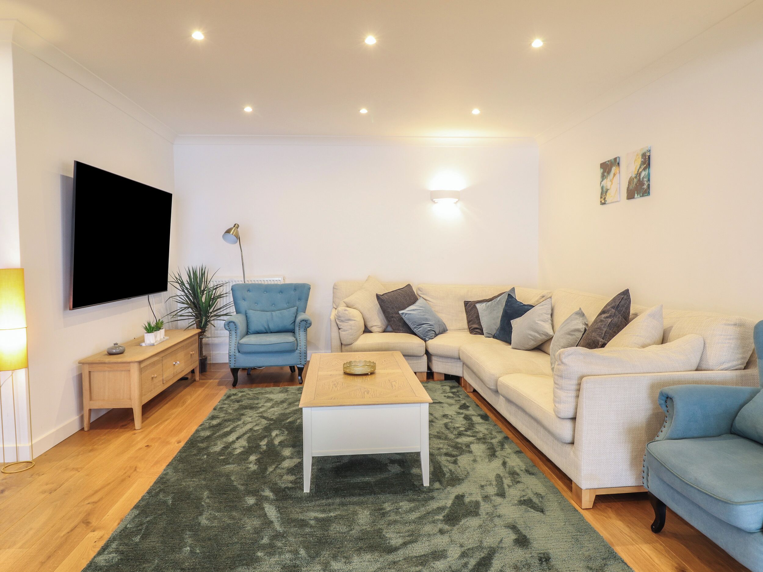 Una sala de estar con un sofá, una mesa de centro, un televisor y una lámpara.
