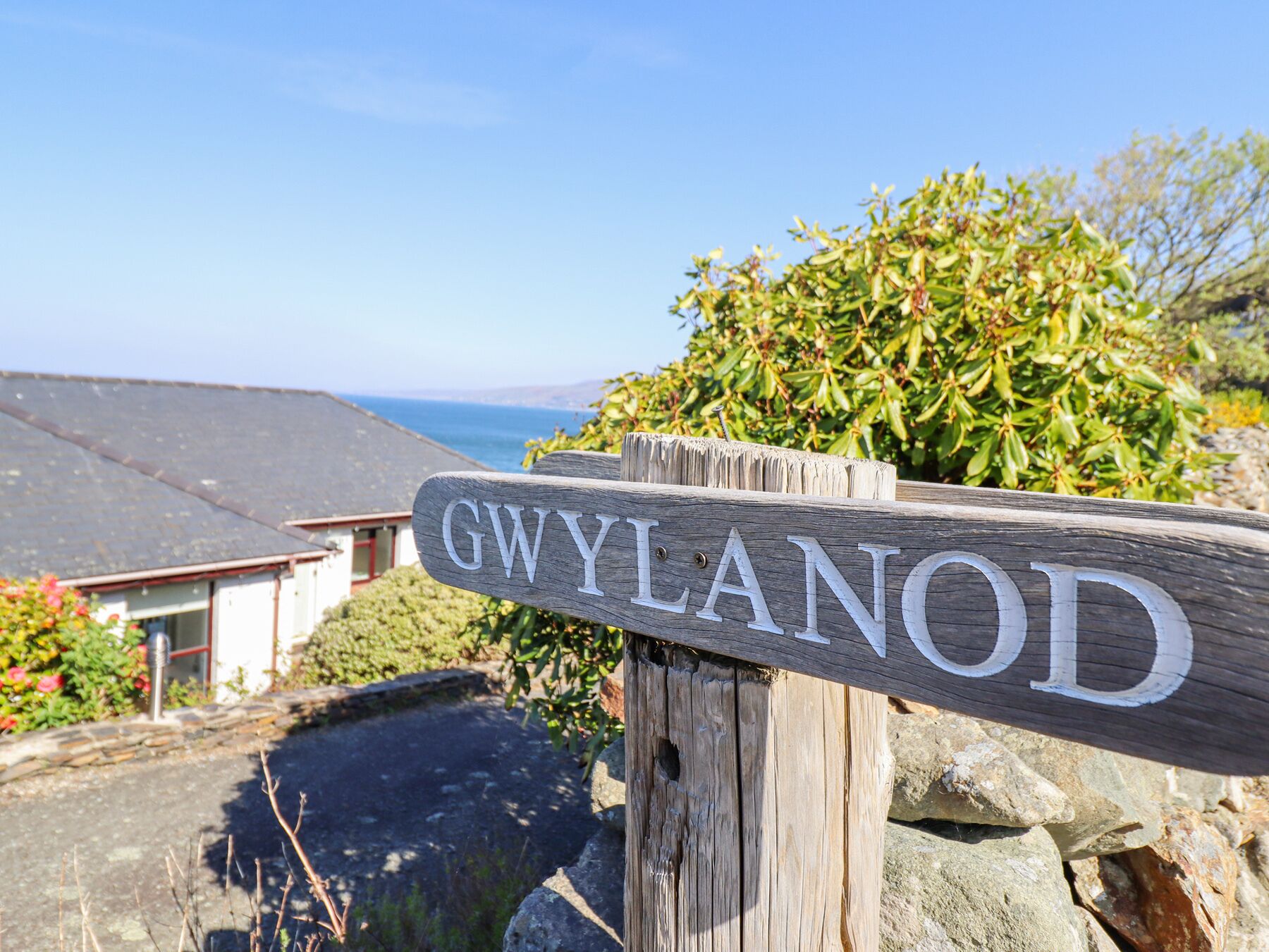 A wooden sign with the name "GWYLANOD" in white letters.