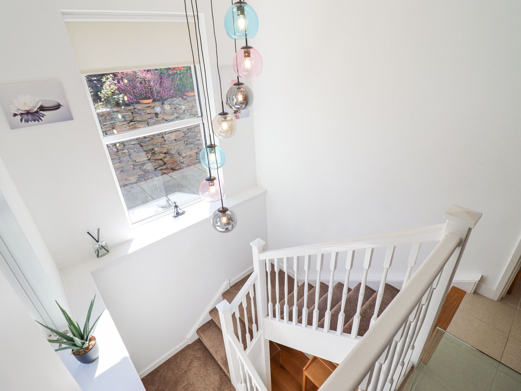 A staircase with white railings and a view of a garden through a window.