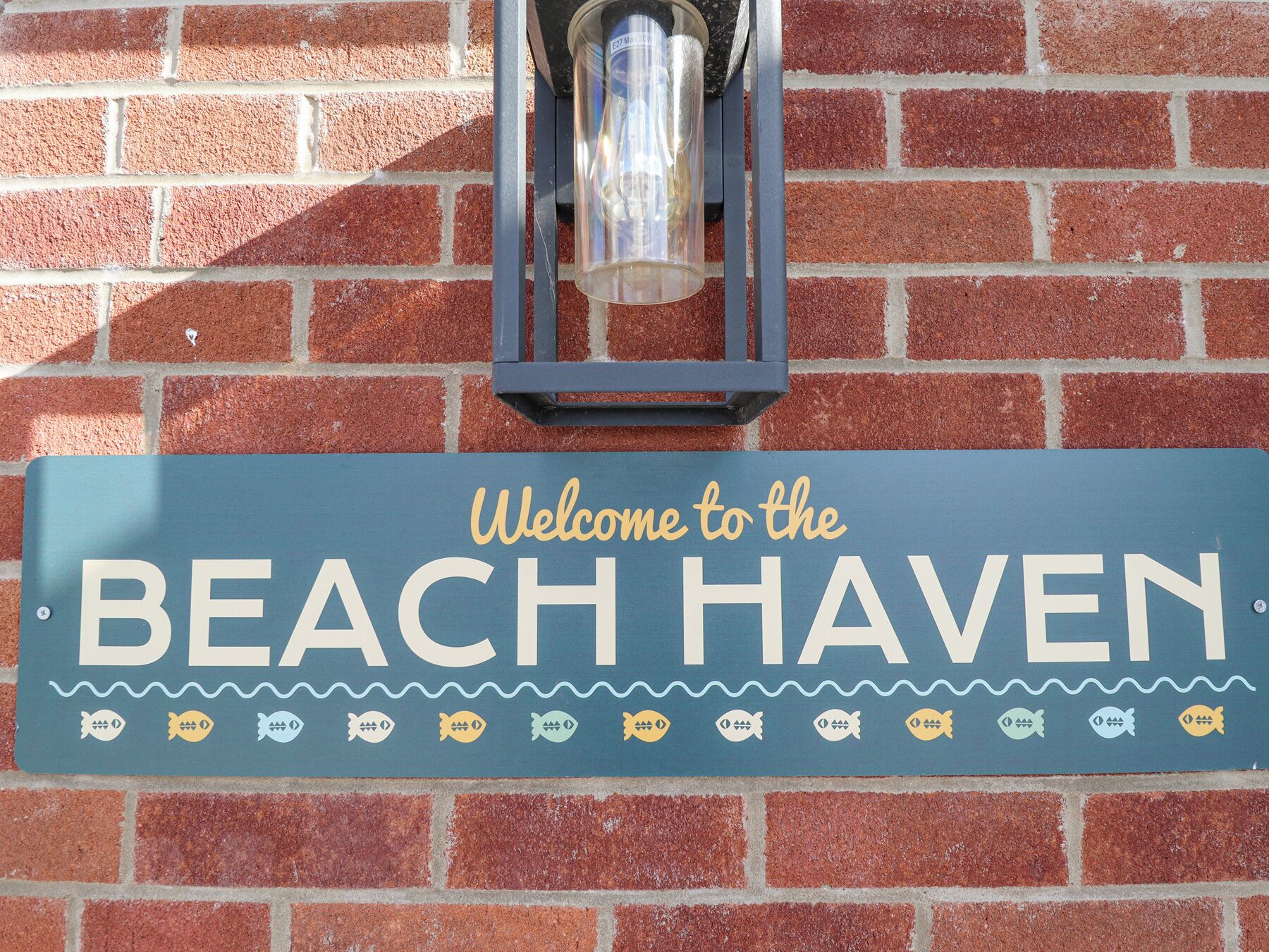 Welkomstbord voor Beach Haven met een lantaarn erboven.