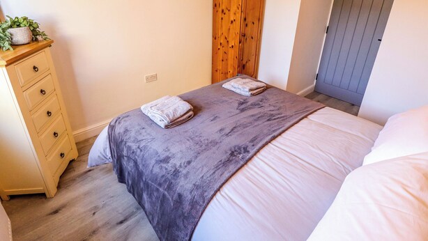 Une chambre à coucher avec un lit, une armoire en bois, une commode et un tableau accroché au mur.