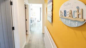 Un couloir avec un mur jaune, une pancarte sur laquelle on peut lire « Tout est plus agréable à la plage », et une porte sur la gauche.
