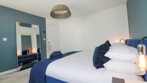 Una camera da letto con un letto grande, uno specchio, una lampada a sospensione e una porta.