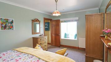 A bedroom with a bed, dresser, mirror, and window.