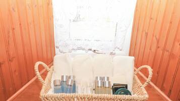 A wooden cabin interior with a woven basket containing toiletries and towels on a wooden bench.