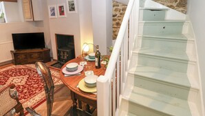 A cozy living room with a fireplace, a dining table set for two, and a staircase leading to an upper level. - 5A Castle Street (Ryde)