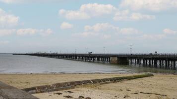 A beach with a long pier extending into the water.