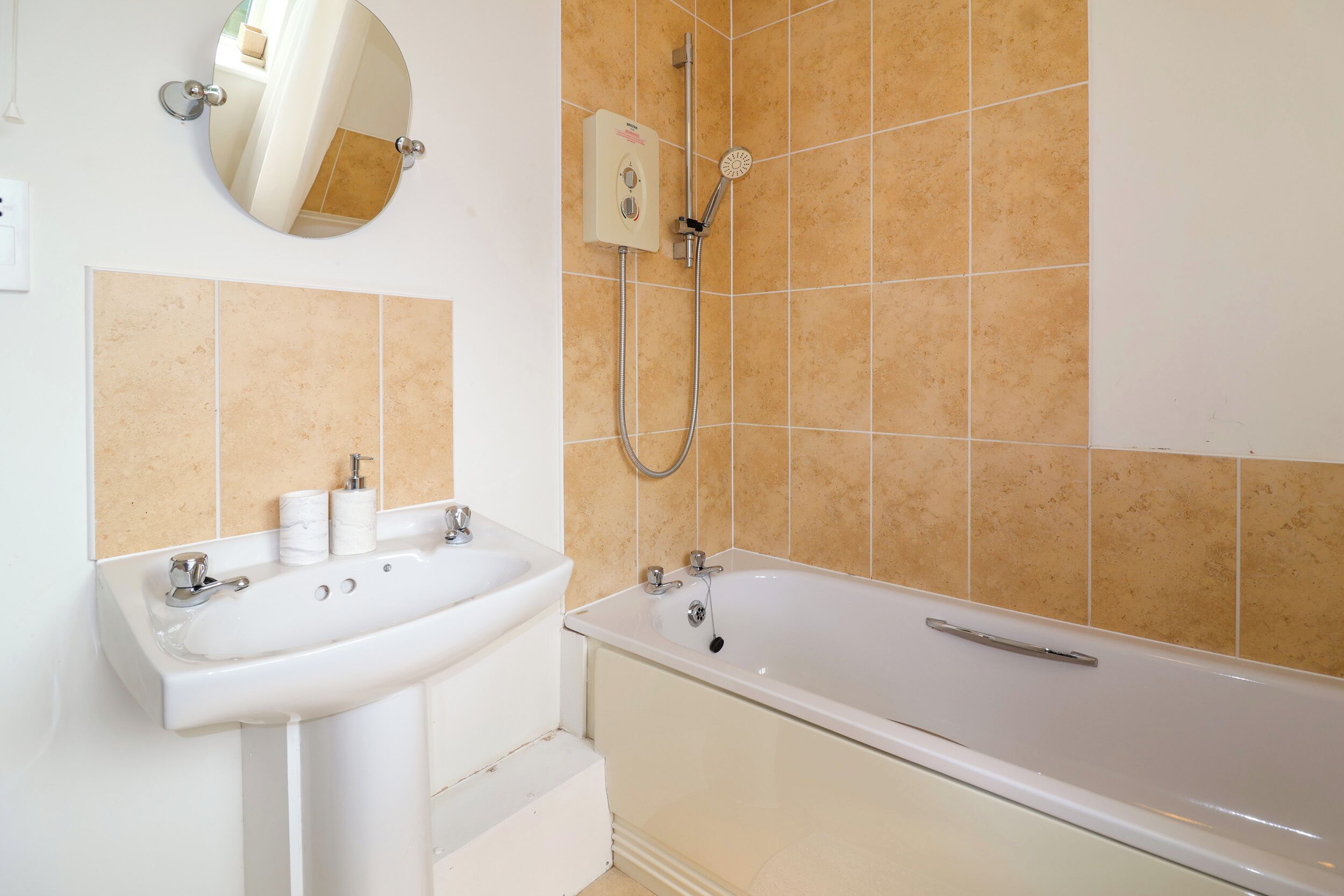 A bathroom with a sink, mirror, and bathtub.