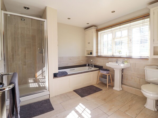 Une salle de bain moderne avec une douche à l’italienne, une baignoire sur pieds, un lavabo et des toilettes.
