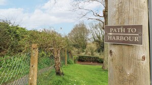 A signpost with a sign reading "Path to Harbour" against a backdrop of trees and a clear sky.