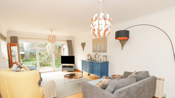 A living room with a sofa, armchair, and a TV on a stand. There is a blue cabinet and a round coffee table.