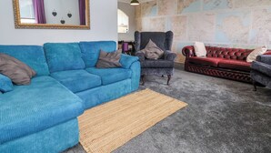 Ein Wohnzimmer mit einem blauen Sofa, einem roten Ledersofa, einem dunklen Sessel und einer großen Wandkarte.