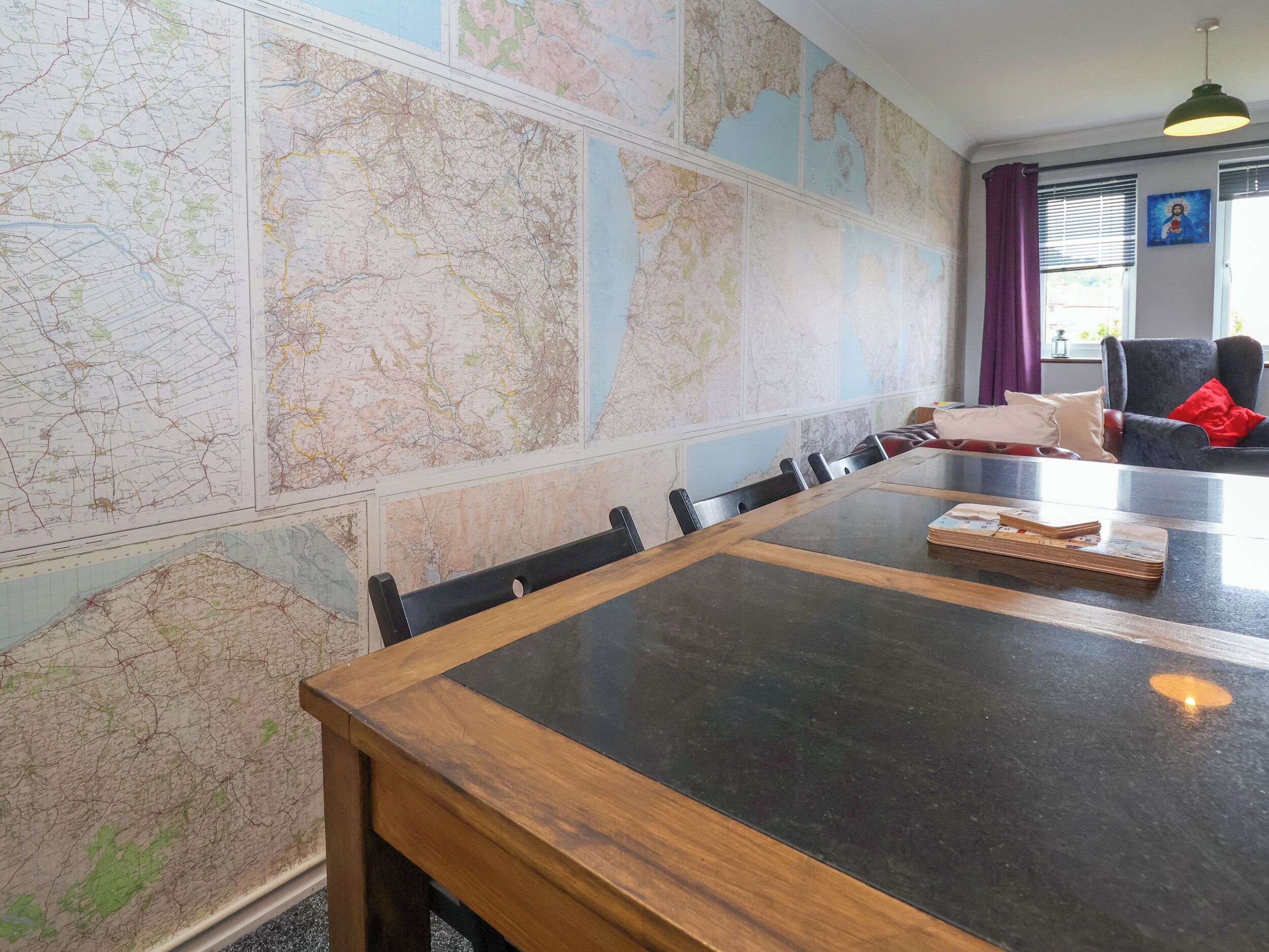 A dining area with a large map on the wall, a wooden table, and a black chair.