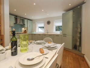 A modern kitchen with a dining area set for a meal. - 5 Red Sails (Poole)