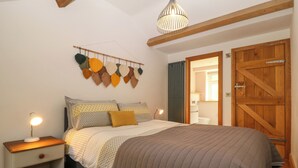 A bedroom with a bed, bedside tables, a hanging light fixture, a wooden door, and a wall-mounted decoration. - 5 Banc Llugwy (Betws-Y-Coed)