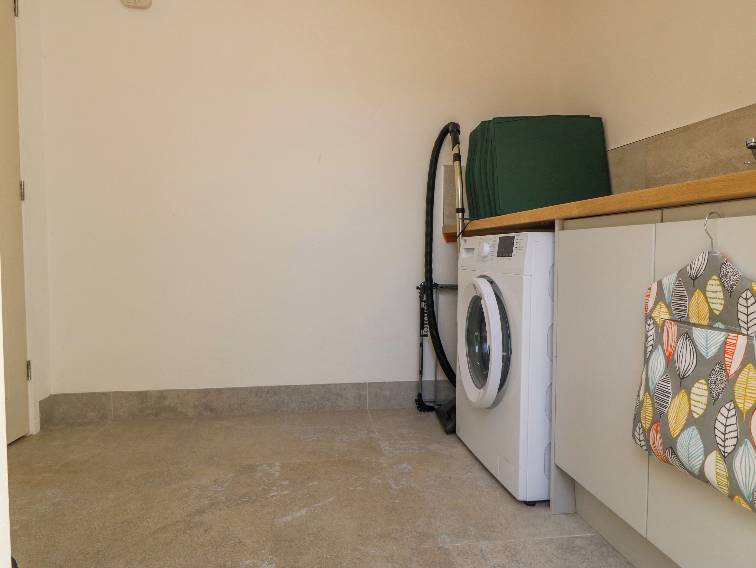Un espace buanderie équipé d’un lave-linge et d’un sèche-linge, doté d’un sol carrelé et d’un étendoir mural.