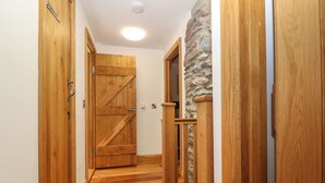 A wooden hallway with a rustic door and a stone accent wall. - 5 Banc Llugwy (Betws-Y-Coed)