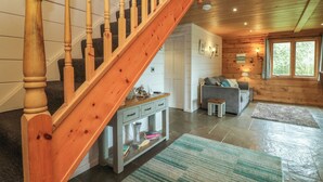 A wooden staircase leading to a living area with a sofa, a small table, and a rug. - Aspen (Winkleigh)