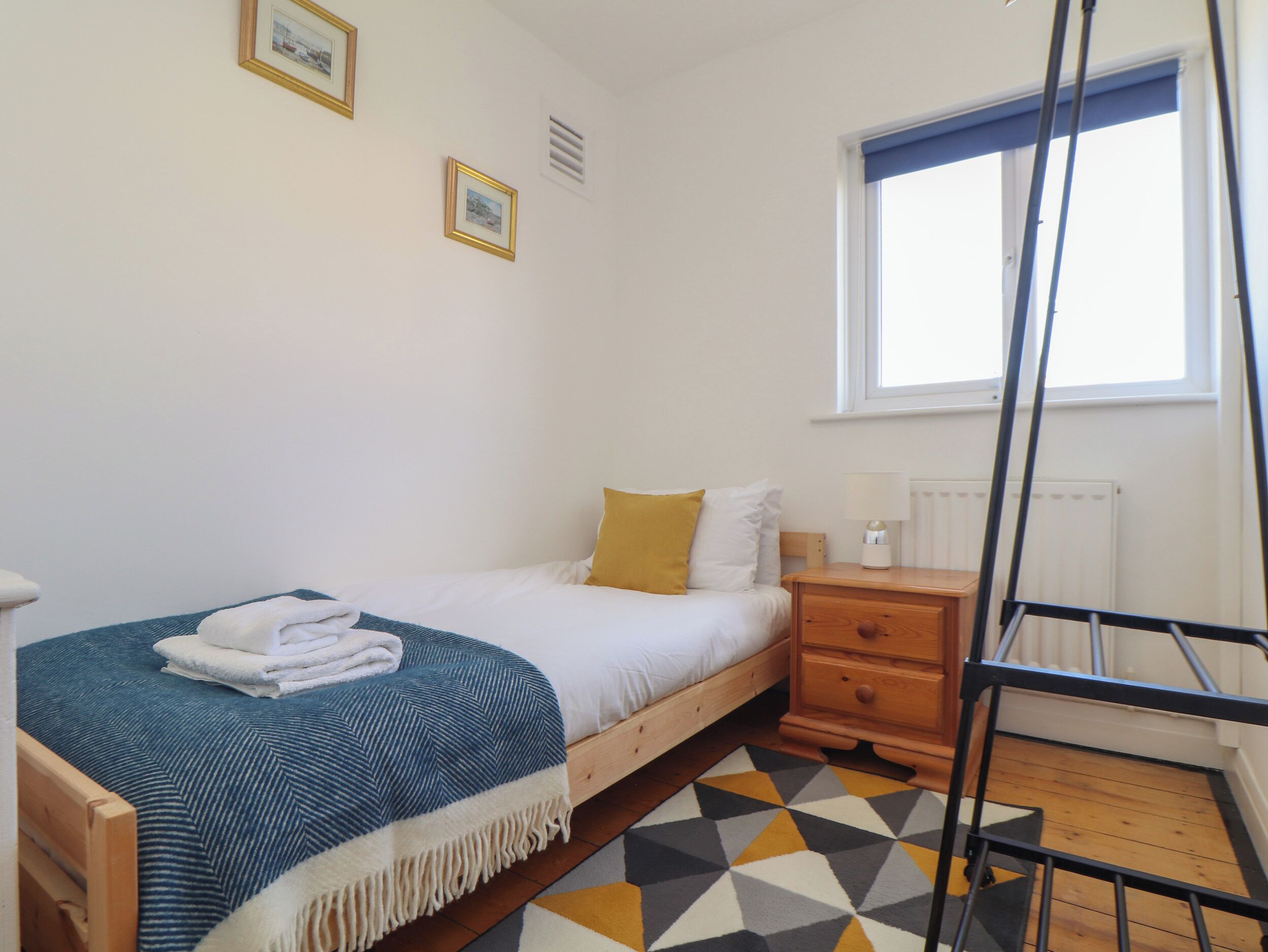 A bedroom with a bed, a bedside table, a lamp, a window, and a radiator.