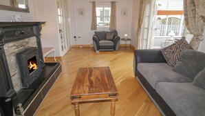 A living room with a fireplace, a sofa, a coffee table, and a view of the outside. - 2 Carlton Cottage (Enniskillen)