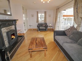 Una sala de estar con chimenea, un sofá, una mesa de centro y vistas al exterior.
