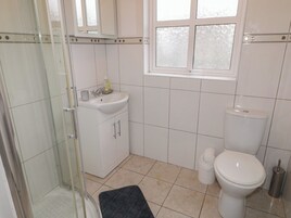 Un baño con cabina de ducha de vidrio, un lavamanos con espejo, inodoro y ventana.