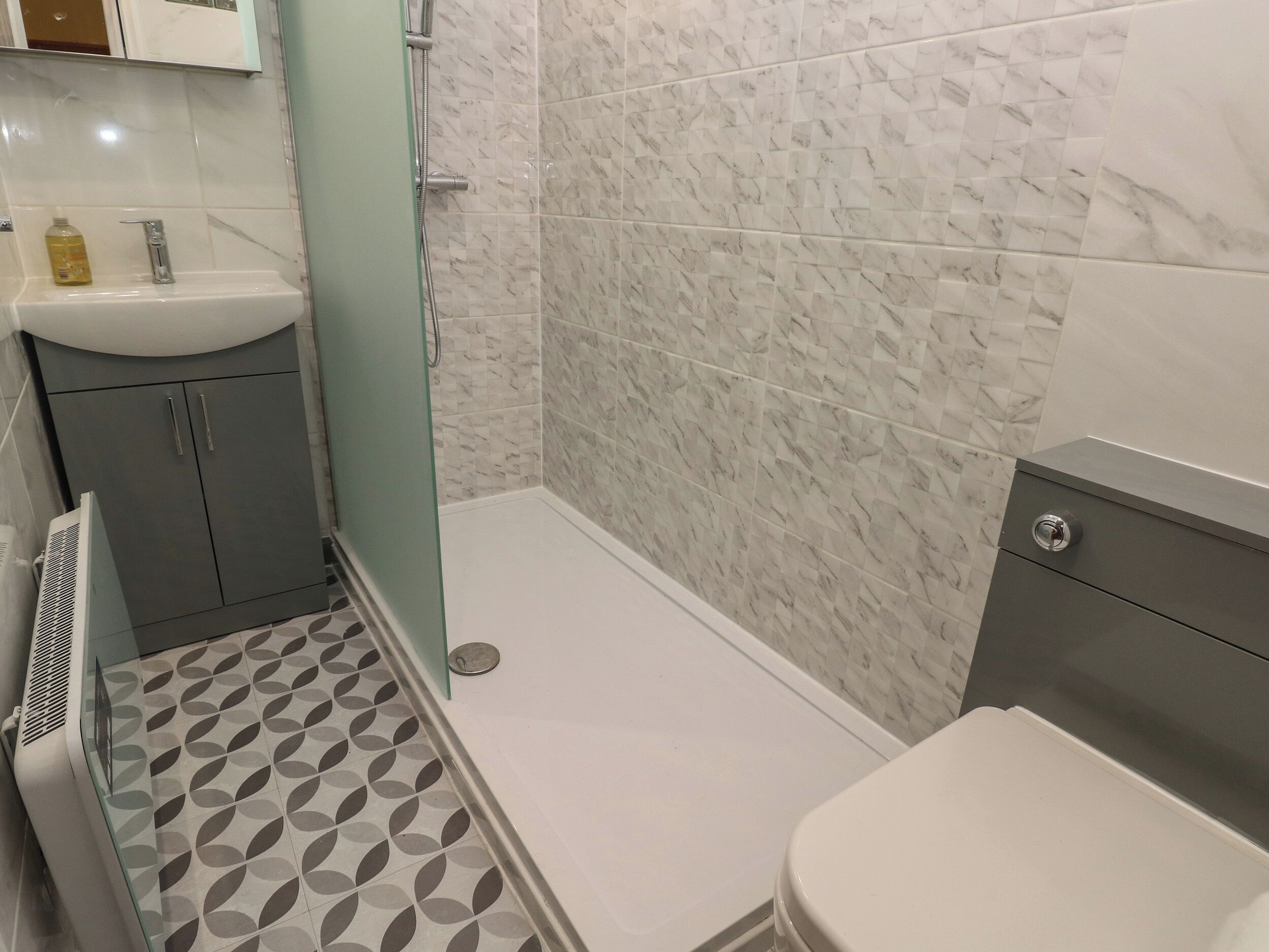 A bathroom with a shower, toilet, and sink.