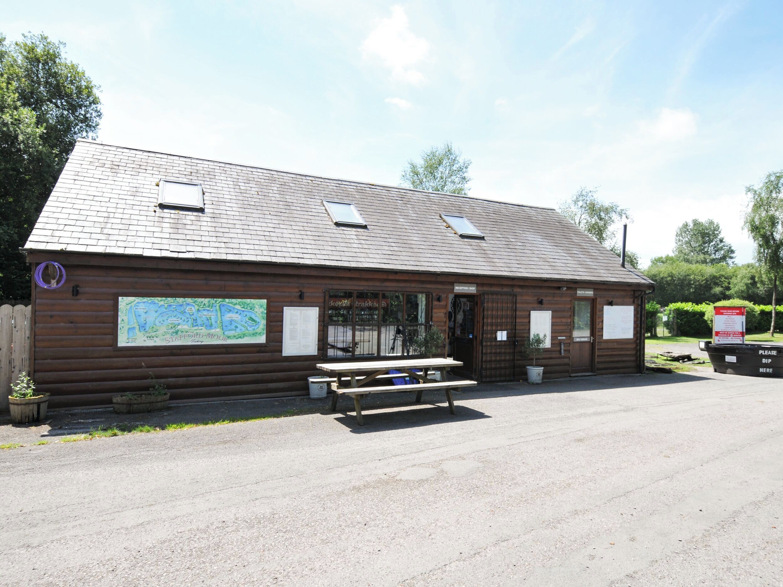 A wooden building with a map, a reception desk, and a picnic table.