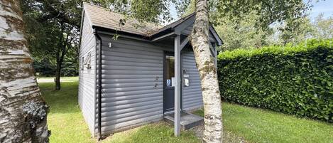 A small, single-story building with a dark exterior, a door, and a small porch area.