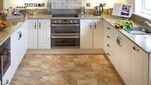 A modern kitchen with white cabinetry, a double oven, and a granite countertop. - The Lake Cottage (Belford)
