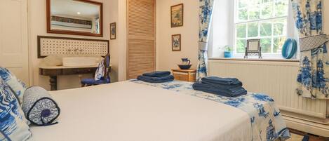 A bedroom with a bed, a desk, a chair, a window with curtains, and a radiator.