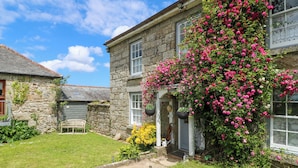 A stone building with a garden, a pathway, and a bench. - Connie's Cottage (Helston)