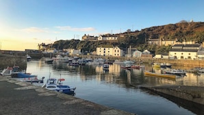 A harbor with boats docked and buildings on a hillside. - Connie's Cottage (Helston)