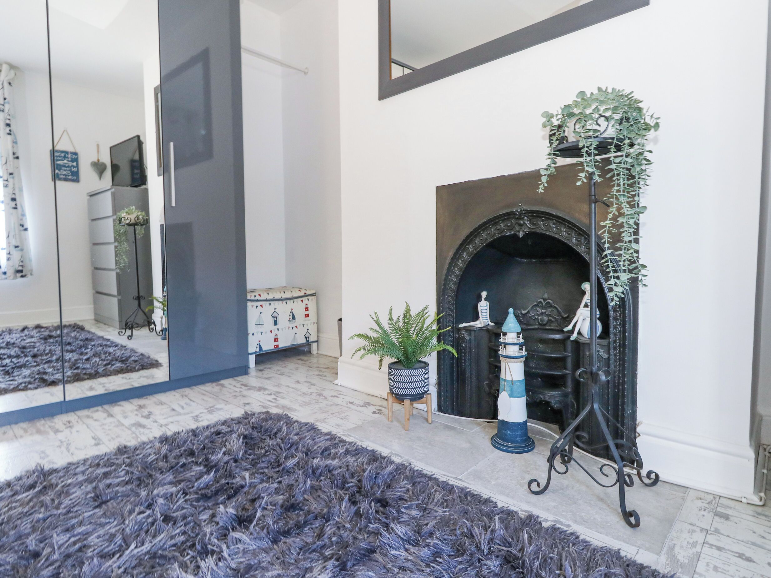 A modern living room with a fireplace, a large mirror, and a dark blue shag rug.