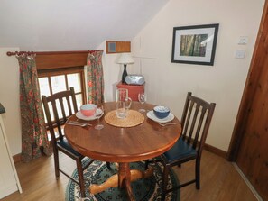 A dining area with a wooden table, chairs, a radio, and a framed picture on the wall.