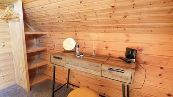 Ein Holzblockhaus im Inneren mit einem Holztisch, einem Spiegel, einer Flasche und einer Fernbedienung.