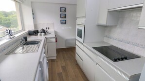 Een moderne keuken met een roestvrijstalen spoelbak, een inbouwoven en een zwart inductiekookplaat.