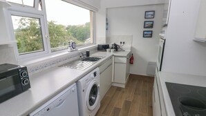 Een kleine keuken met een wasmachine, een magnetron en een kookplaat.