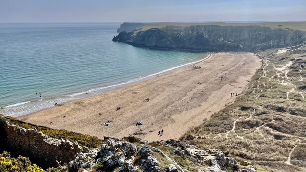 Una playa costera con acantilados rocosos y cielo despejado.