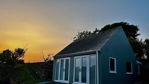 Una casa pequeña de un solo piso con techo inclinado y fachada azul oscuro.