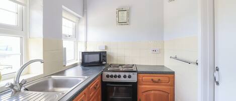Une cuisine équipée d’un évier, d’une cuisinière, d’un four à micro-ondes et de meubles de rangement en bois.