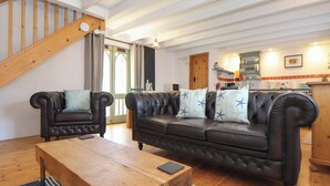 Een gezellige woonkamer met een houten trap, een leren bank en een houten salontafel.