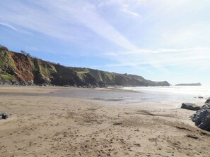 Una playa con un acantilado rocoso y un mar tranquilo.